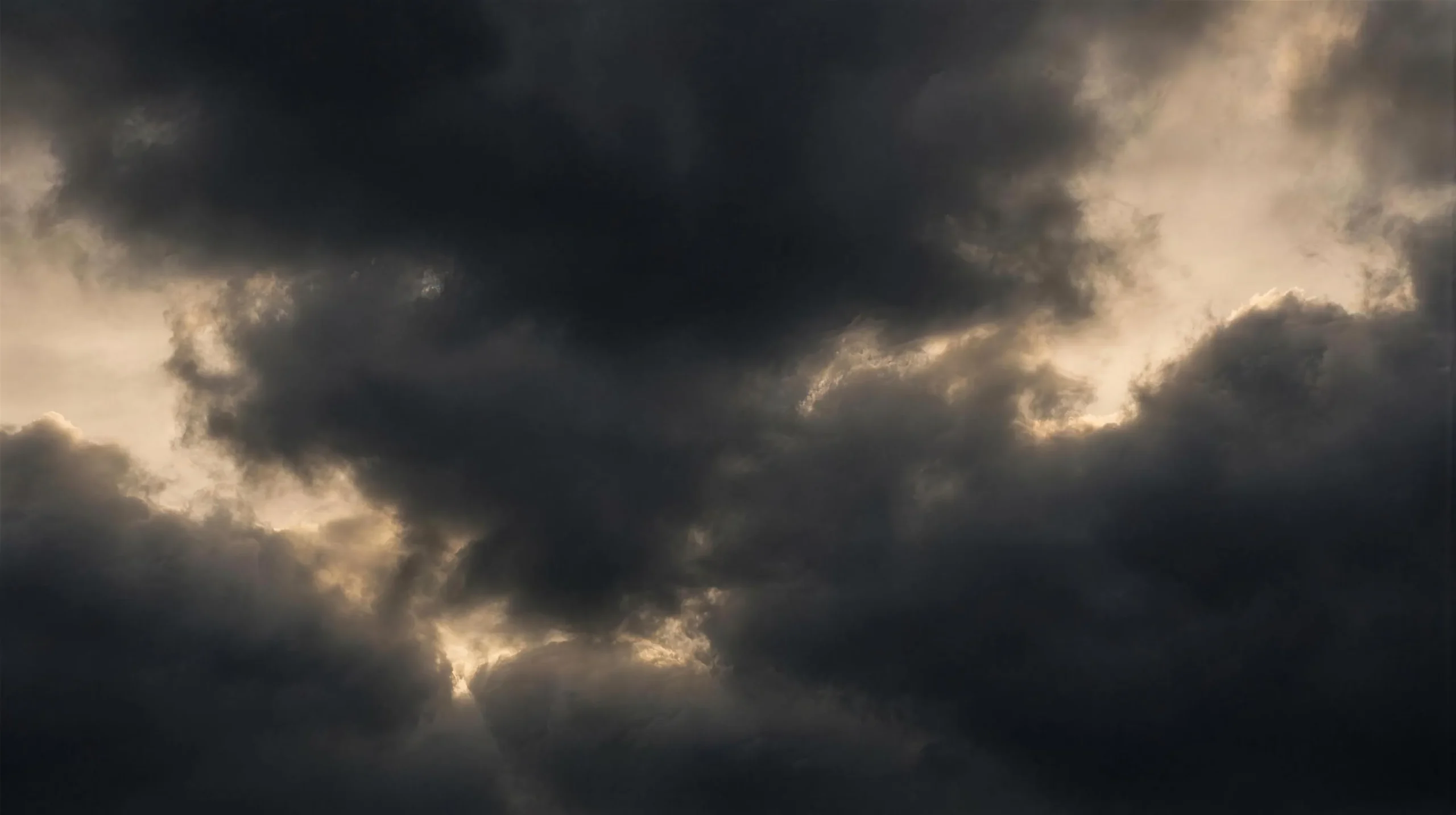 Abstract dark storm clouds backlit with warm gold light