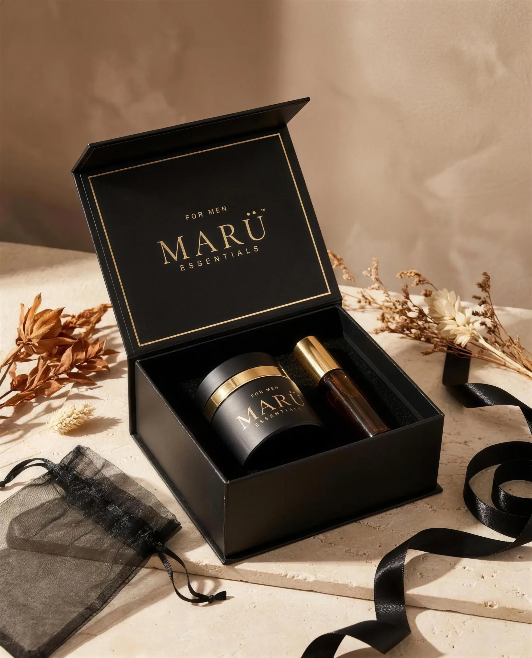 Matte black MARÜ ESSENTIALS gift box with gold trim holding a jar and oil bottle