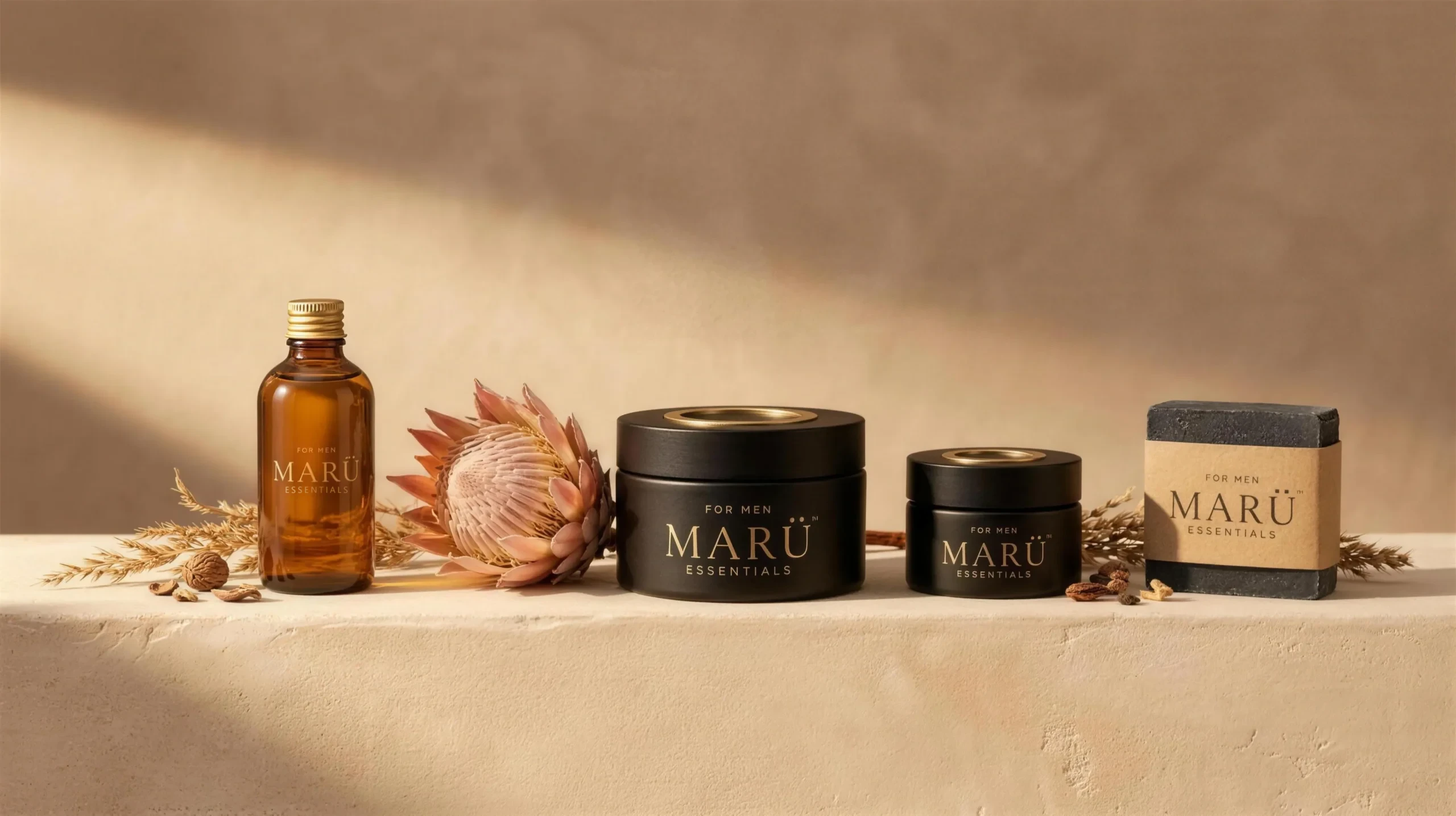 The full MARÜ ESSENTIALS range on a sandstone ledge: oil, butter, balm and cleansing bar with a protea